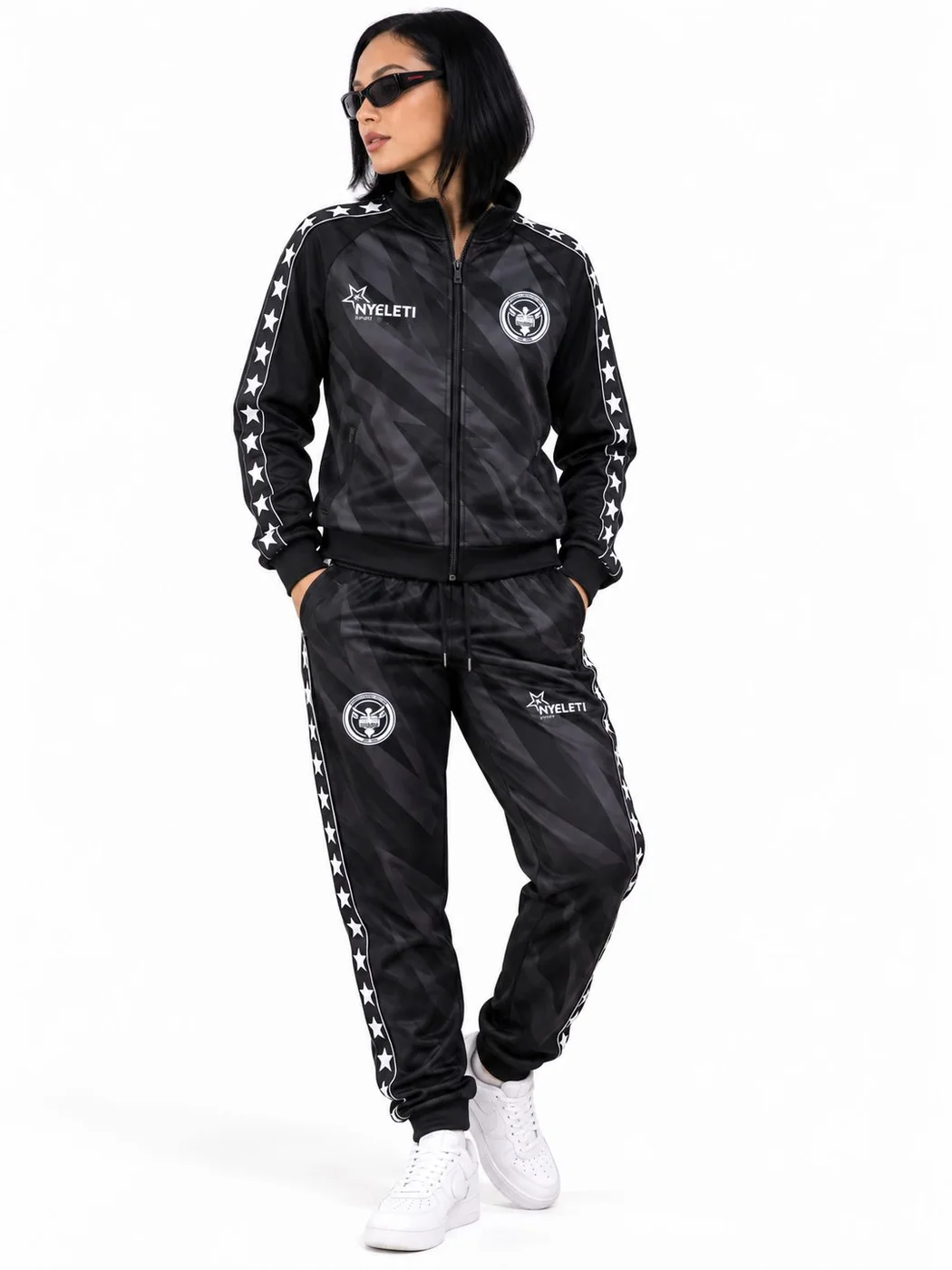 The Sash 1632 tracksuit set in black, jacket zipped, worn with white sneakers