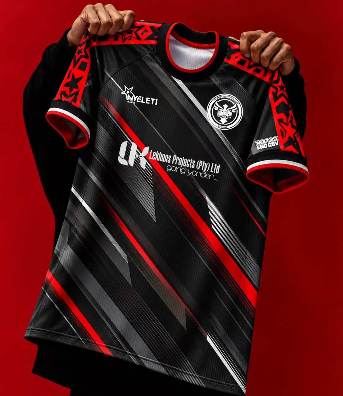 The Warm Up T-shirt in black with red streaks, held up against a red wall